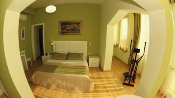 Un dormitorio con cama, mesitas de noche, un cuadro y una cinta de correr.