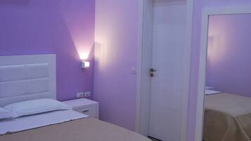 A bedroom with a bed, a nightstand, a wall-mounted air conditioner, and a door.