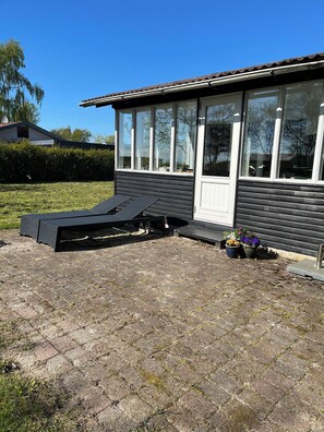 A house with a patio area, a small deck, and potted plants.