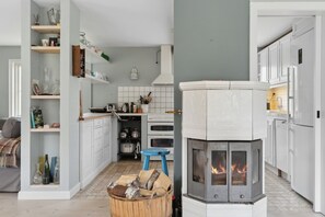 A modern kitchen with white cabinets, a built-in stove, and a blue stool.