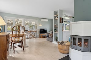 A living room with a fireplace, a television, a dining area with a table and chairs, and a bookshelf.