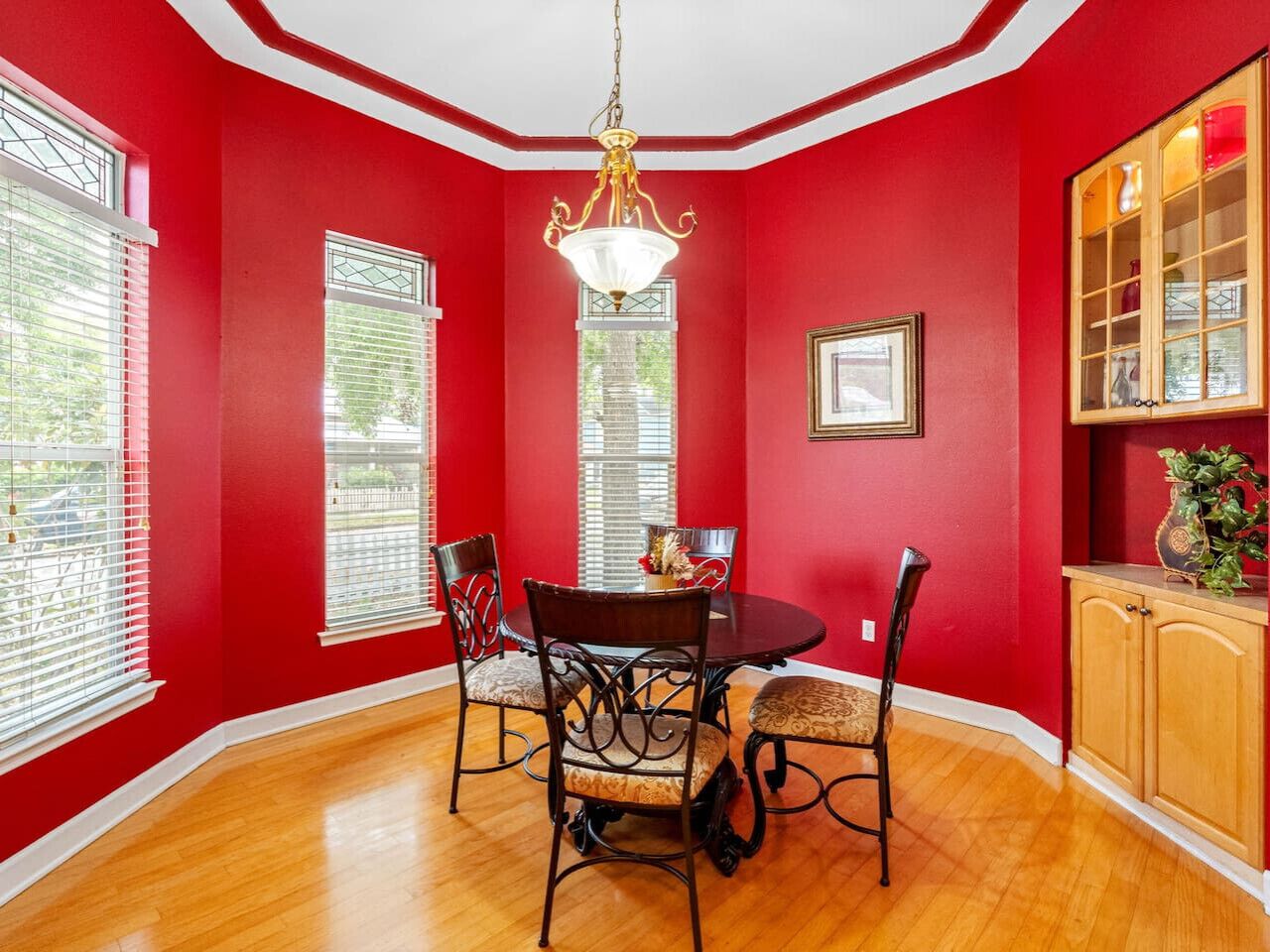 Une salle à manger avec un mur rouge, un lustre, une table ronde et des chaises.