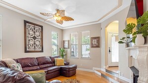 A living room with a leather sofa, a fireplace, and a staircase leading to another room.