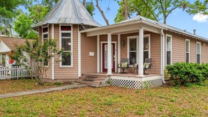 A two-story house with a front porch, a small attached garage, and a covered front entrance.