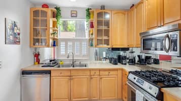 A modern kitchen with wooden cabinets, stainless steel appliances, and a built-in dishwasher.