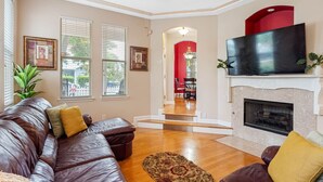 A living room with a leather sofa, a fireplace, and a TV.