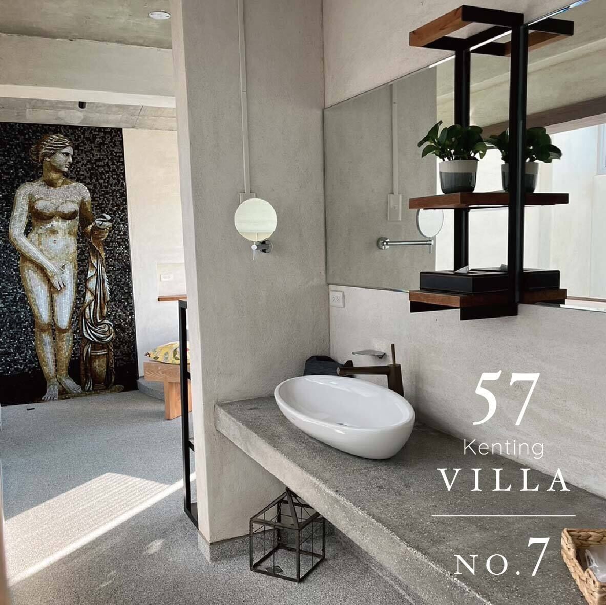A modern bathroom with a large mirror, a white sink, and a mosaic wall.