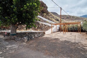 Ein rustikaler Außenbereich mit einer Pergola, einer Steinmauer und einem Baum.