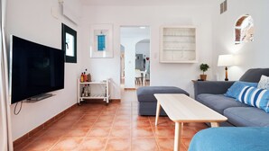 Ein Wohnzimmer mit Flachbildfernseher, einer Couch, einem Couchtisch und einem Essbereich mit Stühlen.