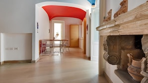 A spacious room with a curved ceiling, a wooden dining table, and a fireplace with decorative items. - Dimora Storica Torre Matta – Elegance, history and sea views in the heart of Otr (Otranto)