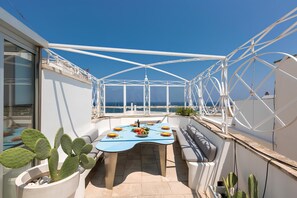 Une terrasse sur le toit, avec une table dressée pour le dîner, entourée de rampes blanches et de cactus en pot.