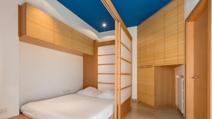 A bedroom with a bed, wooden wardrobe, and a ceiling light. - Dimora Storica Torre Matta – Elegance, history and sea views in the heart of Otr (Otranto)