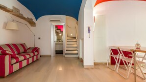 A modern interior with a striped red and beige sofa, a dining table with chairs, and a staircase leading to an upper level. - Dimora Storica Torre Matta – Elegance, history and sea views in the heart of Otr (Otranto)