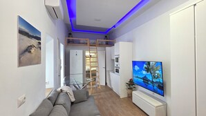 Una sala de estar moderna con un sofá, televisión y una cama elevada.
