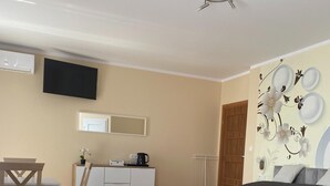 Hotellihuone, jossa on kaksi sänkyä, työpöytä, tuoli, pieni pöytä, patteri ja seinälle asennettu televisio.