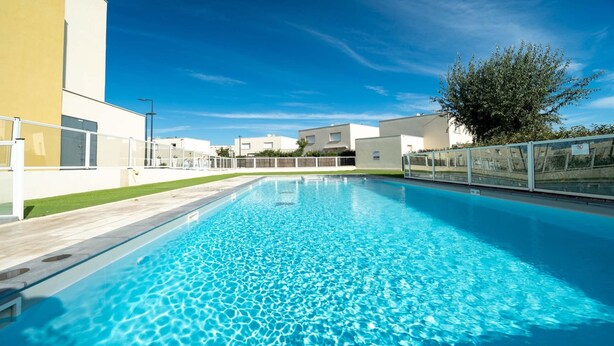 Ein rechteckiger Pool mit klarem, blauem Wasser, umgeben von einem weißen Zaun und einer Rasenfläche.
