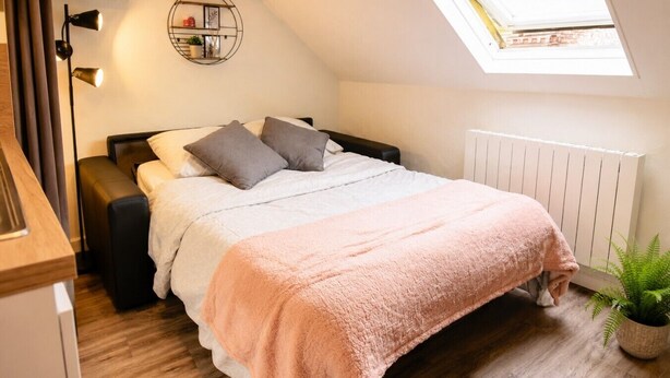 Una camera da letto con un letto, un comodino, una lampada e una finestra.