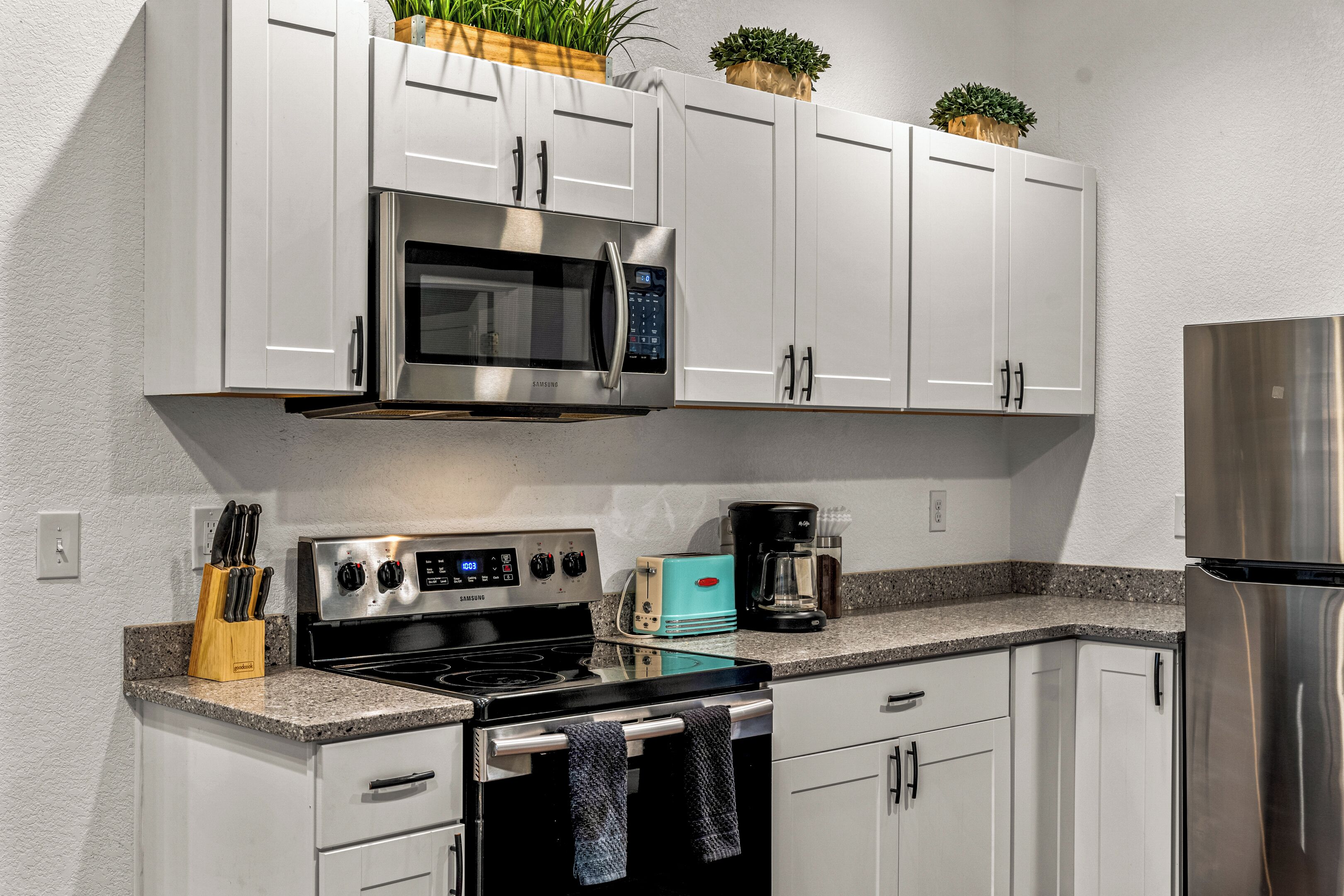 A modern kitchen with white cabinets, stainless steel appliances, and a granite countertop.