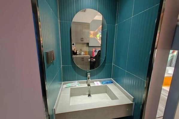 Un baño con un lavamanos rectangular, un espejo y paredes color turquesa.