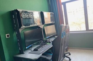 Una habitación con un escritorio, dos monitores, un teclado y una silla.