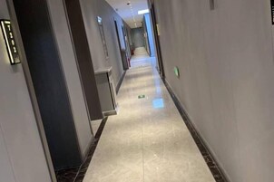 Un pasillo largo y estrecho con un suelo brillante y reflectante, que conduce a una puerta al final.