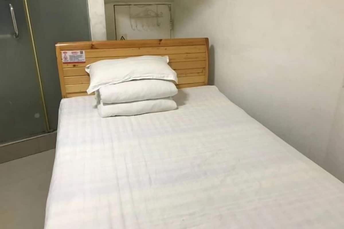 A single bed with a wooden headboard and white bedding.