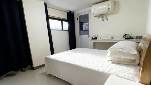 A bedroom with a bed, a desk, and a window. - Oushang Apartment (Shanghai)