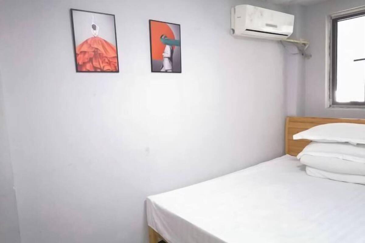 A single bed with white bedding, a wooden headboard, and two framed artworks on the wall.