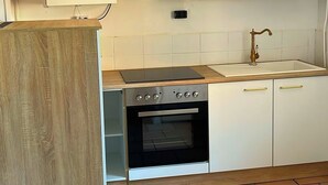 A kitchen with a wooden countertop, a stove, an oven, white cabinets, and a tiled backsplash. - Charming half-timbered house in the heart of the city! "Fachwerkstube" (Witzenhausen)