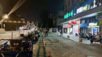 Una calle iluminada de noche con motocicletas estacionadas, escaparates iluminados y una acera para peatones.