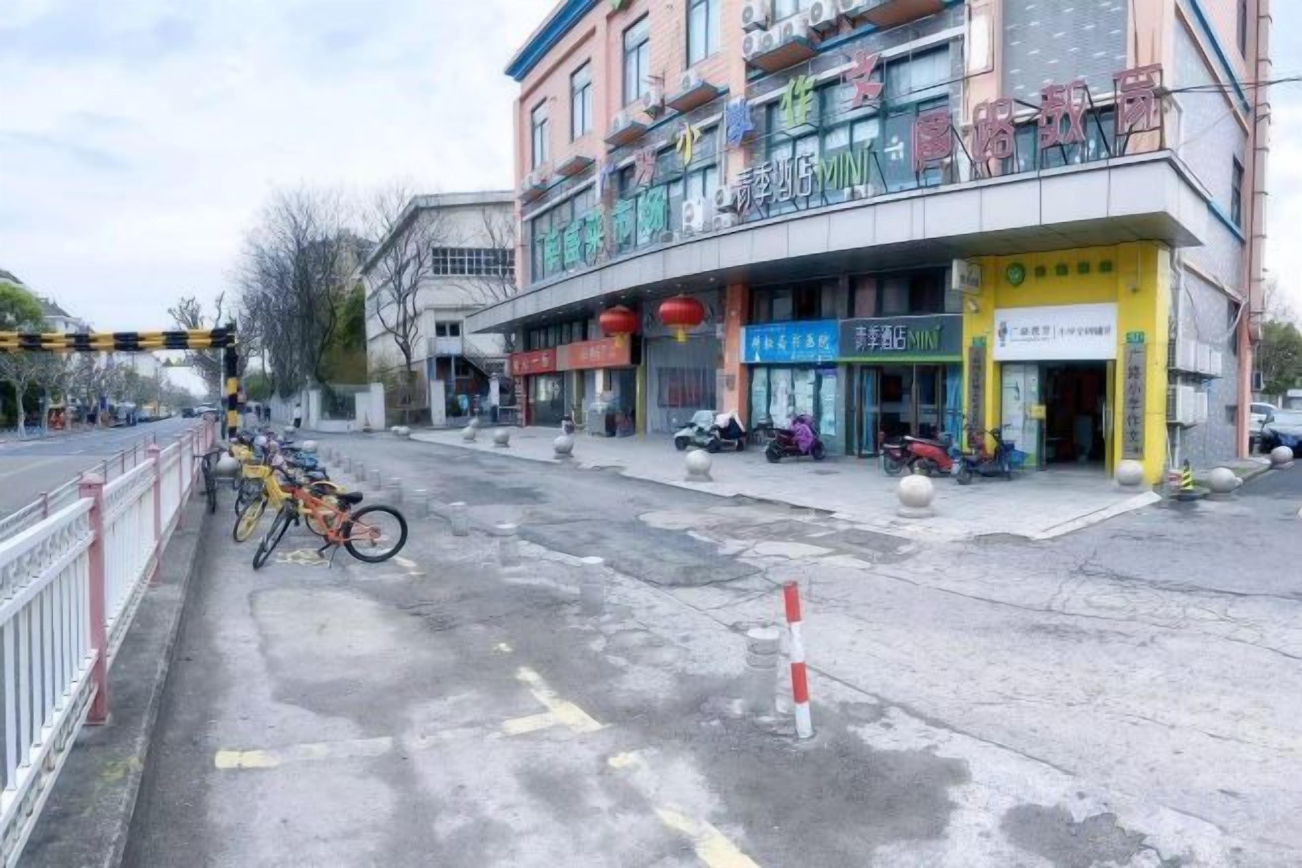 Une rue bordée de boutiques, avec un espace réservé au stationnement des vélos et un passage piéton.