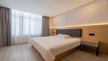 Una habitación de hotel moderna con una cama grande, una mesita de noche y un velador.