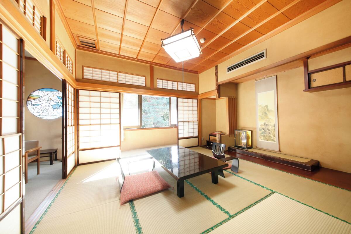 Une pièce de style japonais traditionnel, avec un sol recouvert de tatamis, une table basse et des portes coulissantes.