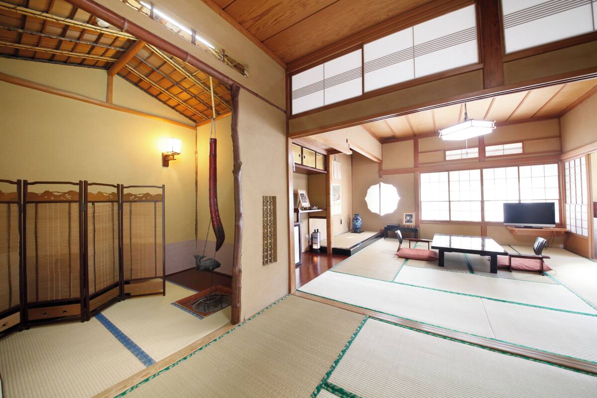 Une pièce de style japonais traditionnel, avec un sol recouvert de tatamis, des portes coulissantes et un téléviseur.