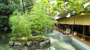 Een traditionele Japanse tuin met een helder waterbassin, steenarrangementen en een houten zitgedeelte.