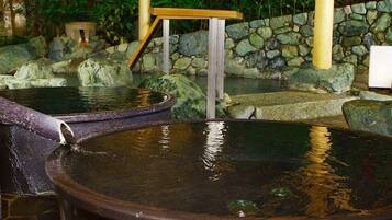 Un onsen japonés tradicional con bañeras de piedra y un banco de madera.