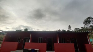 A red building with a flat roof, a staircase leading to the entrance, and a small outdoor seating area with a table and chairs. - pickurstay vbss camping (Gangaraju Madugula)