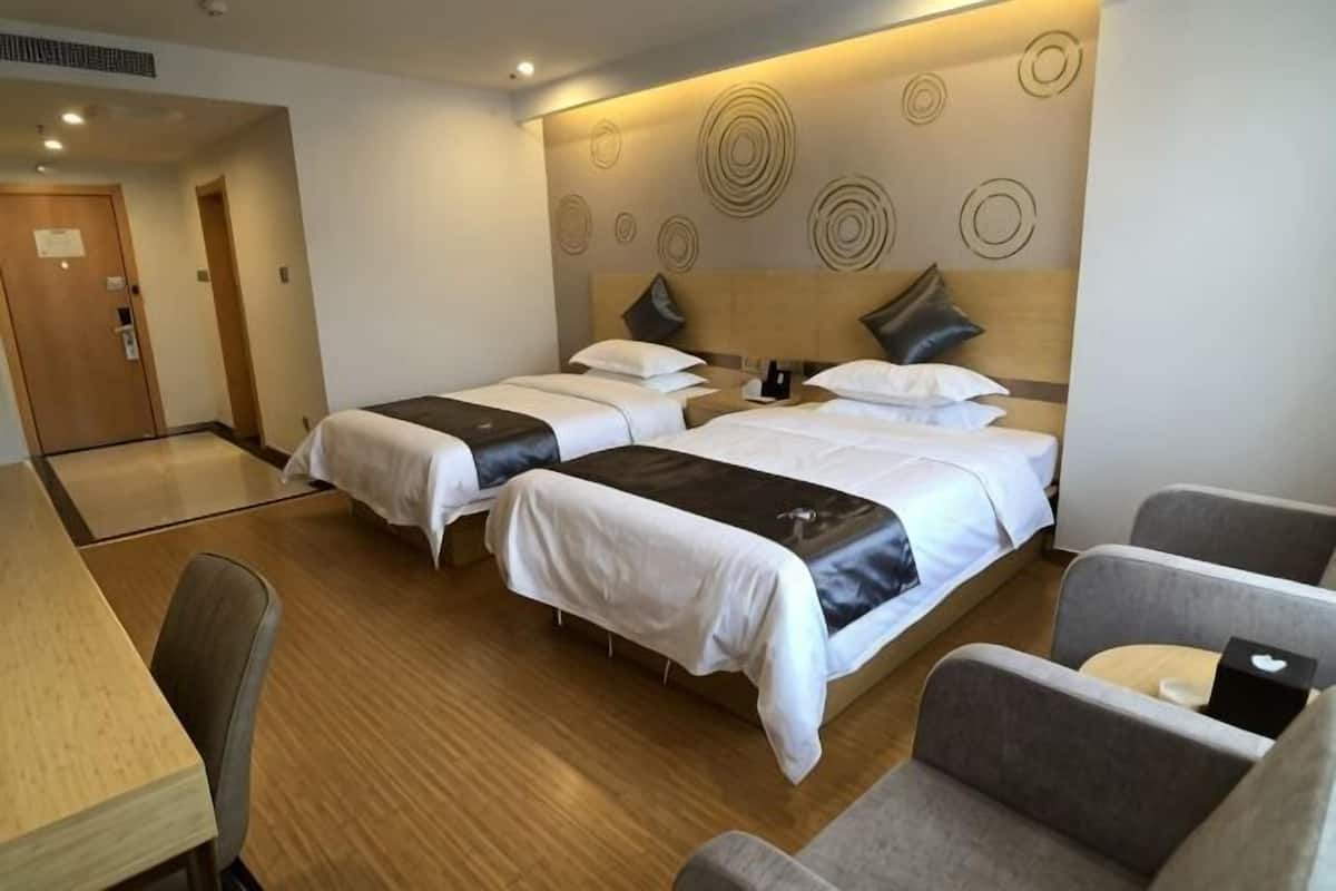 A hotel room with two beds, a desk, and a chair.