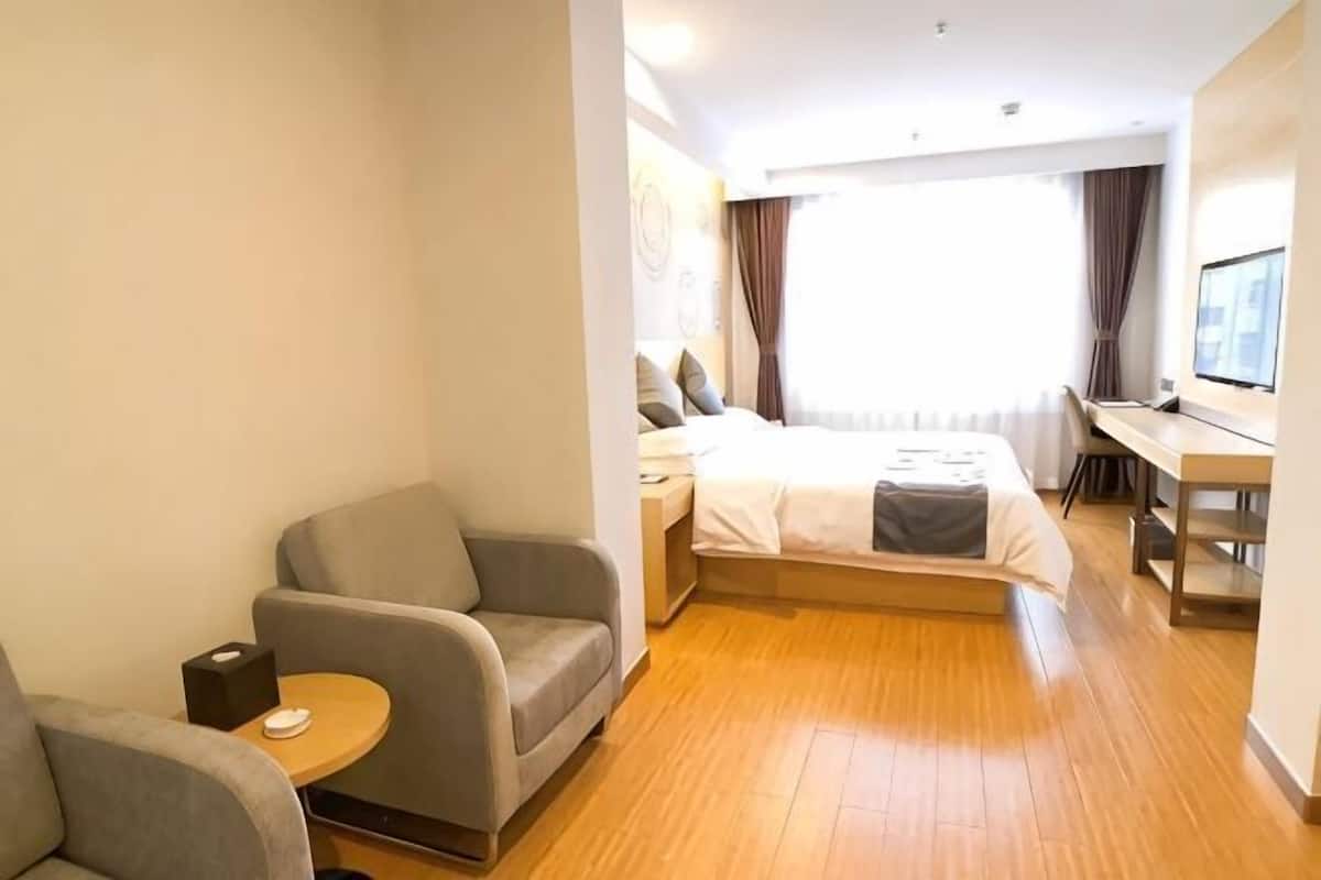 A hotel room with a bed, a desk, a chair, and a small table.