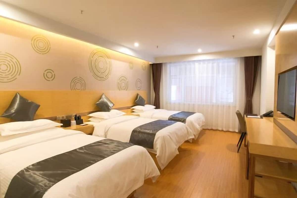 A hotel room with two beds, a desk, a TV, and a large window with curtains.