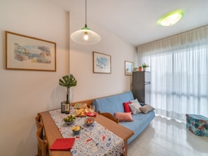 A modern living room with a dining table set for a meal, a blue sofa, and artwork on the walls.