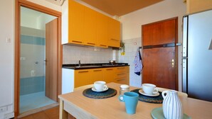 A kitchen with wooden cabinets, a sink, and a refrigerator. - Cozy studio with balcony and sea view (Bibione)