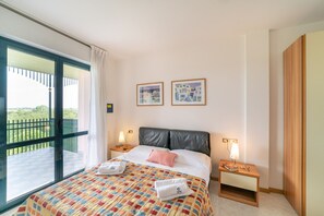 Ein Hotelzimmer mit einem großen Bett, zwei Nachttischen, einem Schrank und einem Balkon mit Blick.