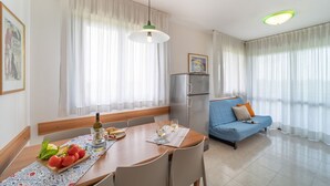 Una sala de estar moderna con comedor, que incluye una mesa de madera, sillas, sofá y refrigerador.