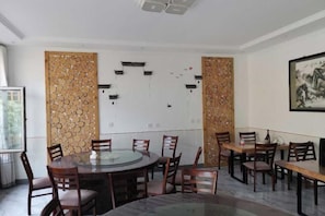 A conference room with a glass table, wooden chairs, and decorative panels. - Baihewan Rural Guest House (Beijing)