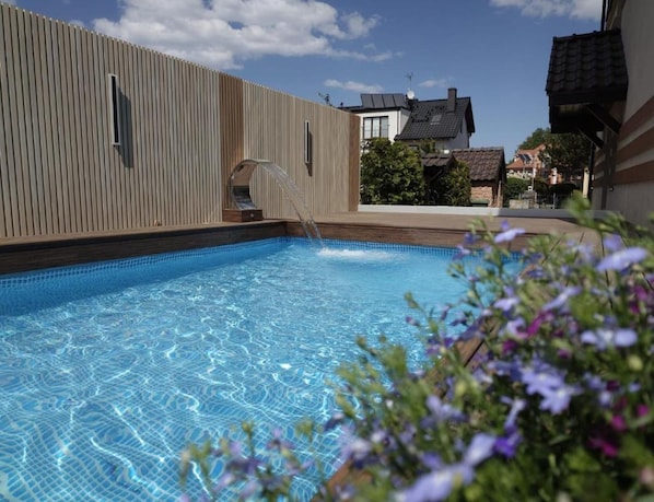 A swimming pool with a wooden deck and a clear blue sky.