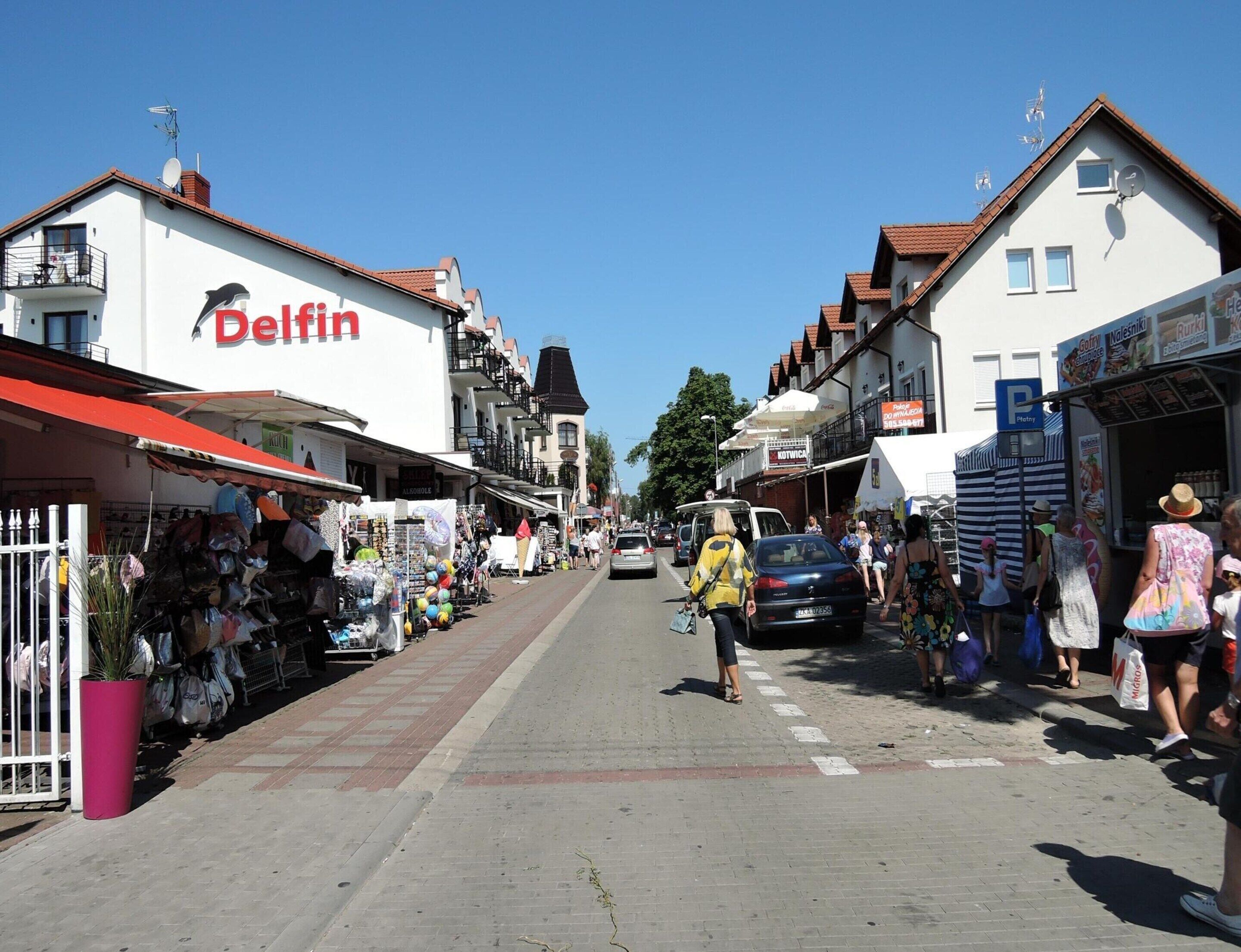 A street with shops, including a visible 'Belfin' store, and pedestrians.