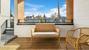 A balcony with a wooden floor, a wicker sofa, and a wicker chair.