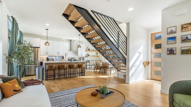 A modern living space with a kitchen, dining area, and a staircase leading to an upper level.