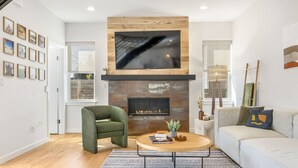 A modern living room with a fireplace, a sofa, a coffee table, and a chair.